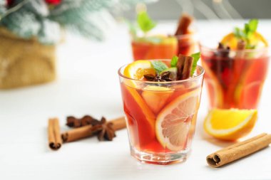 Bardaklarda, baharatlarda ve beyaz ahşap masadaki Noel dekorunda lezzetli punç içecekler, yakın plan. Metin için boşluk