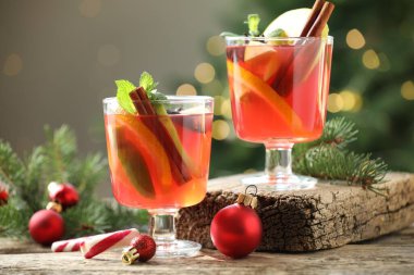 Gözlüklü, baharatlı ve Noel dekorlu lezzetli punç içeceği ahşap masada arka planda bulanık ışıklarla, yakın plan. Bokeh etkisi