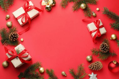 Kırmızı arka planda dekoru ve Noel hediyeleri olan köknar ağacı dalları çerçevesi. Metin için boşluk