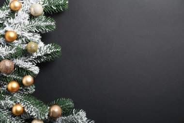 Yapay karla kaplı Noel ağacı dalları ve koyu arka planda mücevherler, düz bir zemin. Metin için boşluk