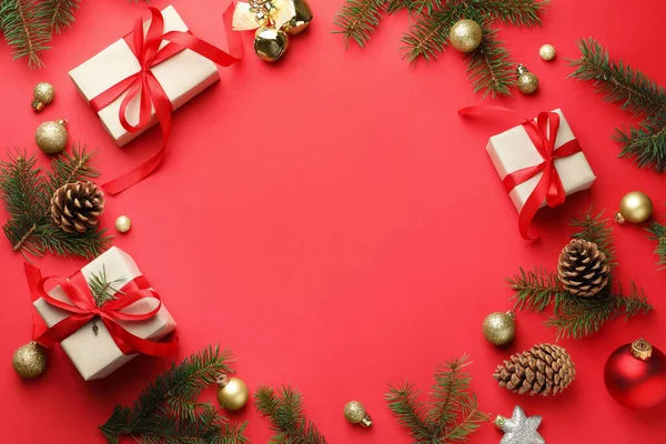 Kırmızı arka planda dekoru ve Noel hediyeleri olan köknar ağacı dalları çerçevesi. Metin için boşluk