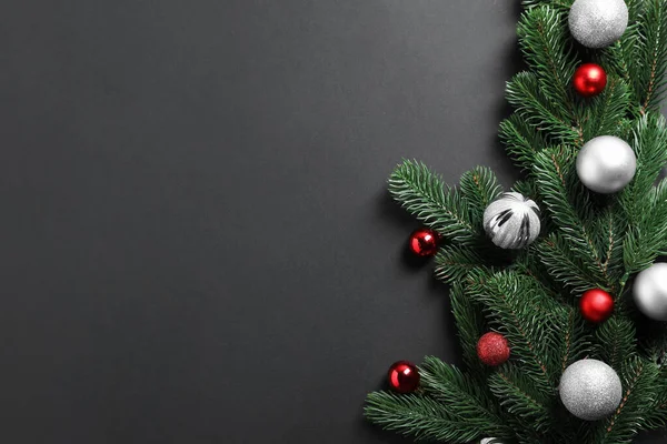 Karanlık arka planda parlak mücevherleri olan Noel ağacı dalları, düz uzanmış. Metin için boşluk