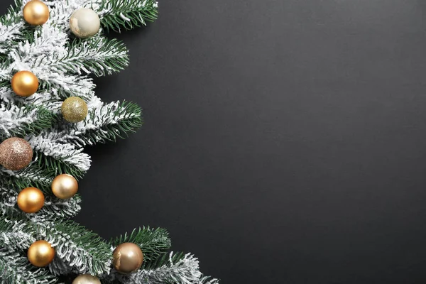 Yapay karla kaplı Noel ağacı dalları ve koyu arka planda mücevherler, düz bir zemin. Metin için boşluk