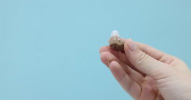 Açık mavi arka planda işitme cihazı olan kadın, yakın plan