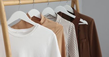 İçerideki ışık duvarının yanında asılı duran farklı şık kıyafetler, yakın plan. Kamera hareket ediyor