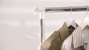 İçerideki raflarda asılı farklı şık kıyafetler, yakın plan. Kamera sağa hareket ediyor