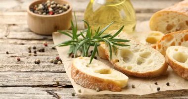 Ciabatta dilimleri, yağ, biber ve biberiye. Kamera sağa hareket ediyor