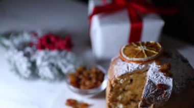 Noel yemeği. Lezzetli Panettone pastası ve beyaz masada şenlikli bir dekor, yakın plan. Kamera aşağı ve sağa hareket ediyor