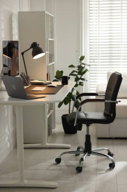 Bilgisayarı, bilgisayarı, bilgisayarı, kupası, kırtasiyesi ve paspası olan şık bir iş yeri.