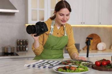 Mutfaktaki masada yemekle kompozisyon oluşturan kadın. Profesyonel yemek fotoğrafçılığı.