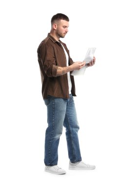 Genç adam beyaz arka planda gazete okuyor.