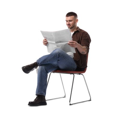 Genç adam beyaz arka planda, sandalyede gazete okuyor.