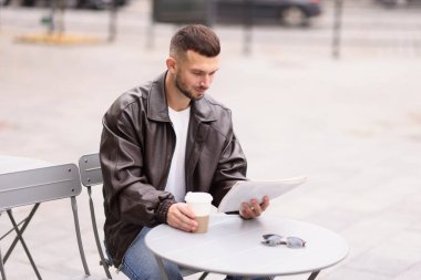 Açık kafedeki masada gazete okuyan genç bir adam. Metin için boşluk