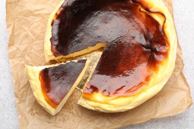 Açık gri desenli masa üzerinde Bask peynirli keki kes, üst görünüm