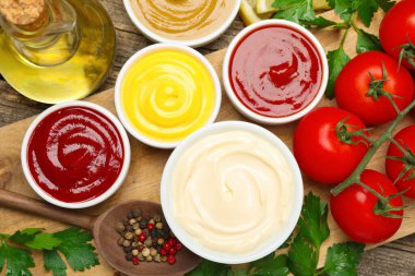 Tabaklardaki farklı soslar ve ahşap masa üzerindeki malzemeler düz.