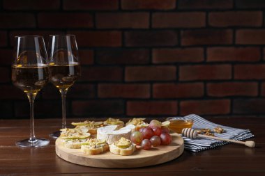 Camembert peyniri, üzüm ve ahşap masada şarap ile servis edilen lezzetli bruschettalar. Metin için boşluk