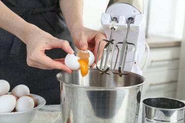 Mutfaktaki masada yumurta kıran kadın, yakın plan.