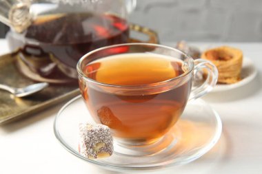 Cam fincanda lezzetli çay ve beyaz masada Türk tatlısı, yakın plan.