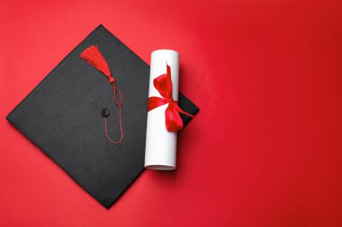 Kırmızı arka planda diploma ve mezuniyet şapkası, üst manzara. Metin için boşluk