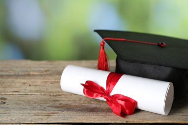 Diploma ve mezuniyet şapkası ahşap masada bulanık arka planda, yakın plan. Metin için boşluk