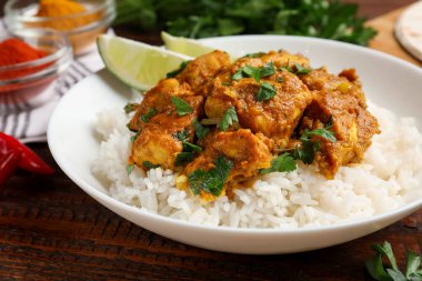 Pirinçli tavuk tikka masala, ahşap masada servis edilir, yakın plan.