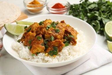 Beyaz mermer masada servis edilen pirinçli tavuk tikka masala, yakın plan.