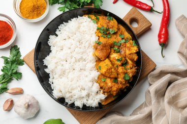 Beyaz mermer masada servis edilen pirinçli tavuk tikka masala.