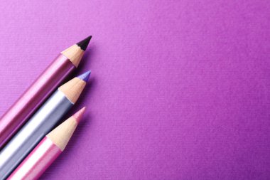 Mor arka planda göz kalemleri, düz yatış. Metin için boşluk