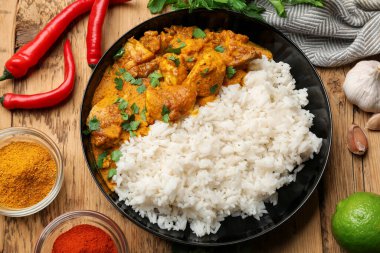 Tavuklu tikka masala, pirinç ve baharatlar ahşap masada, düz yerde.
