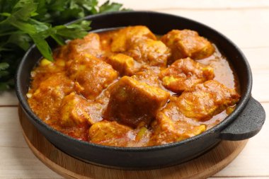 Hafif ahşap masada maydanozlu tavuk tikka masala, yakın plan.