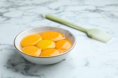 Yumurta sarısı kasede ve beyaz mermer masada fırça, yakın plan.