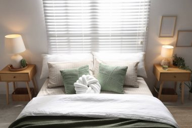 Büyük yataklı, yastıklı ve lambalı şık bir yatak odası. İç tasarım