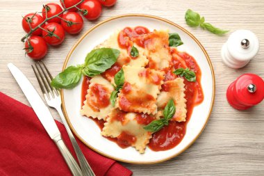 Hafif ahşap masada servis edilen domates soslu ve fesleğenli lezzetli ravioli.