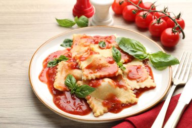 Hafif ahşap masada servis edilen domates soslu ve fesleğenli lezzetli ravioli.
