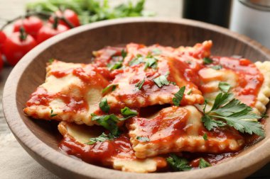 Domates soslu lezzetli ravioli ve ahşap masada maydanoz, yakın plan.