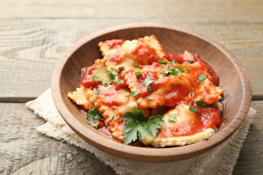 Domates soslu lezzetli ravioli ve ahşap masada maydanoz, yakın plan.