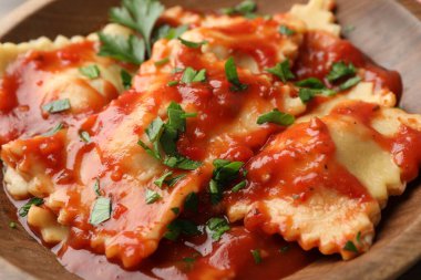 Domates soslu lezzetli ravioli ve ahşap masada maydanoz, yakın plan.