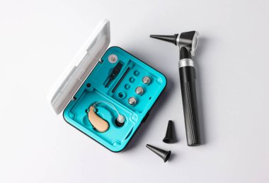 Modern otoskop, işitme cihazı ve açık gri arka plan kulak spekulumları, düz yatış