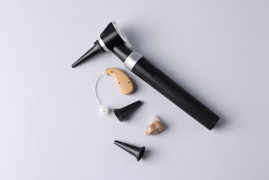 Modern otoskop, işitme cihazı ve açık gri arka plan kulak spekulumları, düz yatış