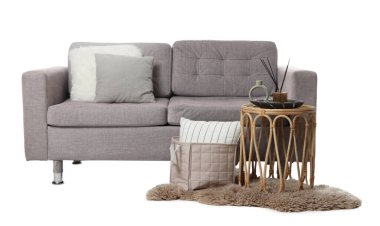 Beyaz yastıklı şık bir kanepe, kahve masası ve halı.