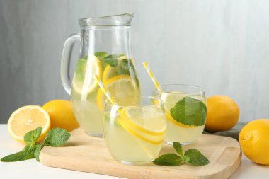 Taze limonata, sürahi, limon ve nane şekeri beyaz masada, yakın plan.