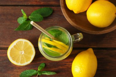 Mason kavanozunda taze limonata, ahşap masada limon ve nane.