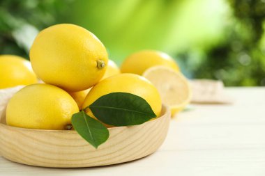 Beyaz ahşap masa üzerinde yeşil yapraklı taze limonlar, yakın plan. Metin için boşluk