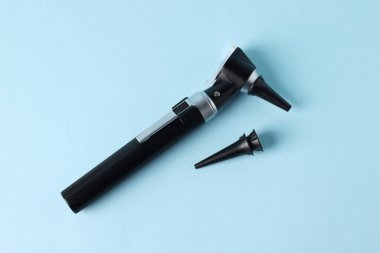 Duyma testi. Açık mavi zemin üzerinde modern otoskop ve kulak spekulumları, düz yatıyordu