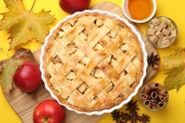 Lezzetli ev yapımı elmalı turta ve sarı arka planda malzemeler.