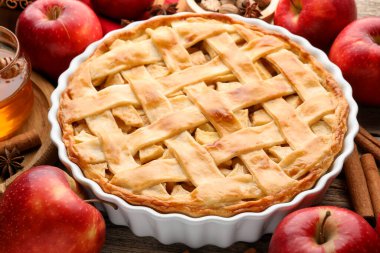 Lezzetli ev yapımı elmalı turta ve ahşap masada malzemeler, yakın plan.