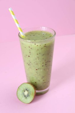 Lezzetli bir buzlu içecek ve pembe arka planda kivi, yakın plan.