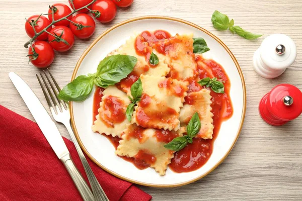 Hafif ahşap masada servis edilen domates soslu ve fesleğenli lezzetli ravioli.