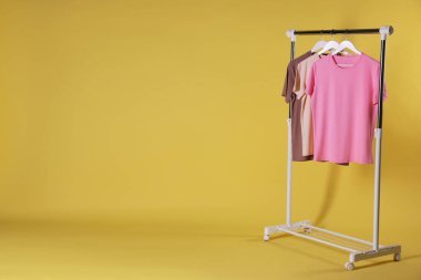 Farklı kadın kıyafetleri sarı arka planda asılı duruyor. Metin için boşluk