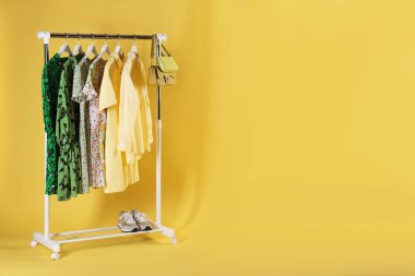 Farklı kadın kıyafetleri sarı arka planda asılı duruyor. Metin için boşluk